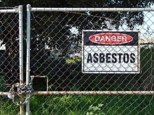 Chain-link gate with a &ldquo;Danger &ndash; Asbestos&rdquo; sign; image by Michael Coghlan, via Flickr, CC BY-SA 2.0, no changes.