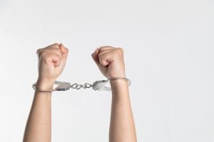 Person&rsquo;s forearms raised to the sky, wearing handcuffs; image by niu niu, via Unsplash.com.