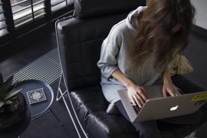 Woman sitting on black leather chair working on laptop; image by Daria Nepriakhina, via Unsplash.com.