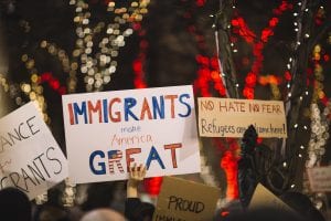 Sign saying "Immigrants make America Great" and one saying "No Hate, No Fear, Refugees are Welcome here;" image by Nitish Meena, via Unsplash.com.