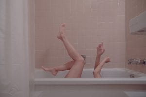 Woman&rsquo;s arms and legs protruding from white bathtub as she is on her back; image by Julieta Christy, via Unsplash.com.