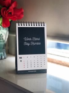 2019 calendar on white table. Print says &ldquo;Work Hard, Stay Humble.&rdquo; Image by Manasvita S, via Unsplash.com.