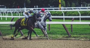 Two jockeys & horses in a close race; image by Noah Silliman, via Unsplash.com.