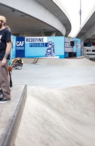 Skateboard ramp with banner saying &ldquo;Redefine Possible,&rdquo; showing wheelchair athletes. Image by Allie Smith, via Unsplash.com.