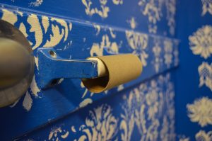 An empty toilet paper roll core on a holder in a blue-painted bathroom.