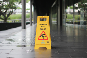 Yellow &ldquo;Caution: Wet Floor&rdquo; sign on wet floor; image by T.H. Chia, via Unsplash.com.