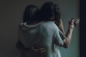 Two women embracing, holding each other close.