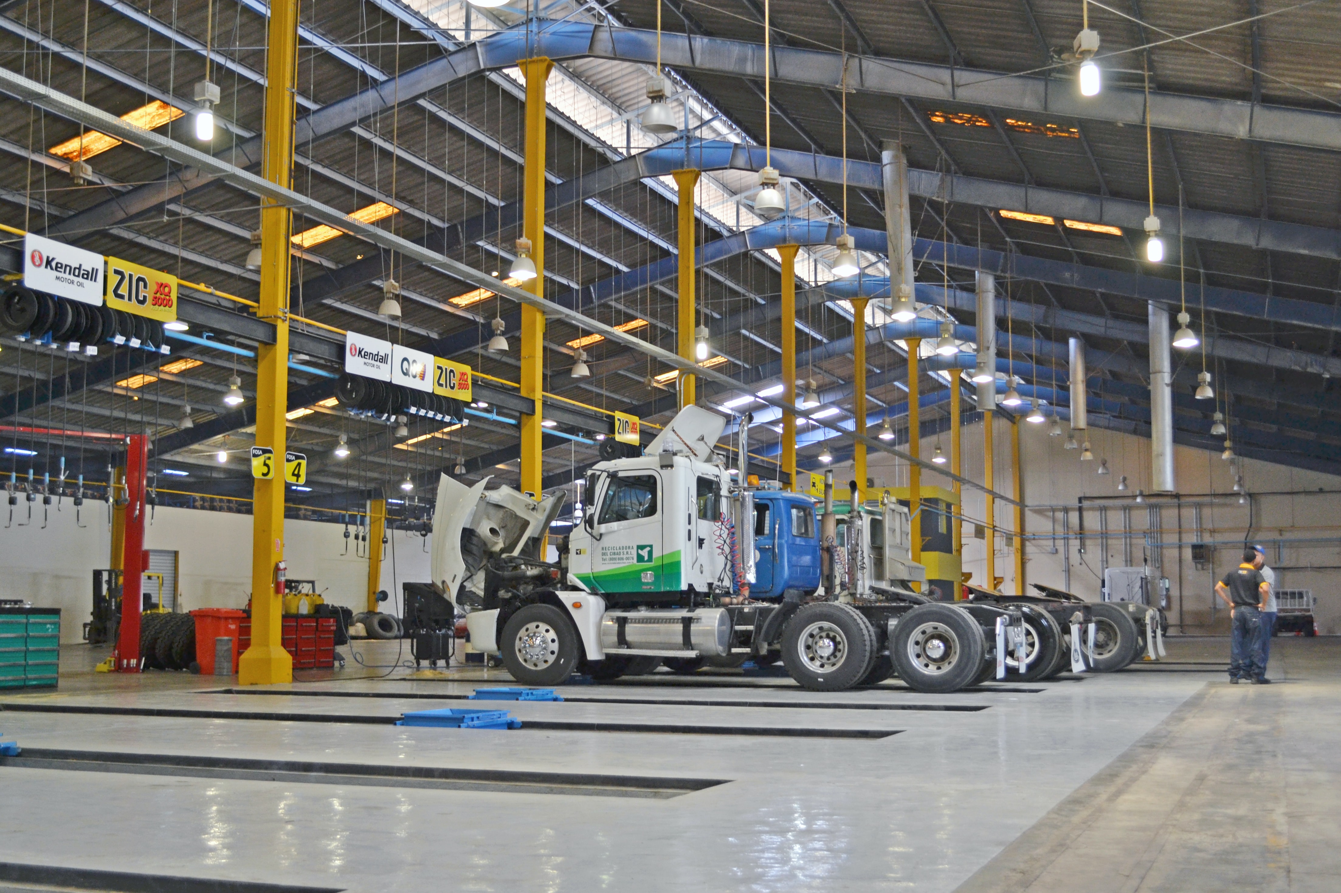 Trucks in mechanics bays for service; image by Carlos Daniel, via Unsplash.com.