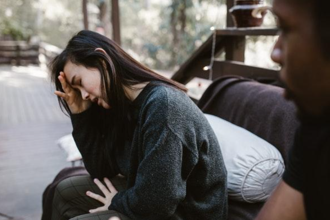 Stressed out woman on sofa, man looking on; Photo by RODNAE Productions on Pexels.com.
