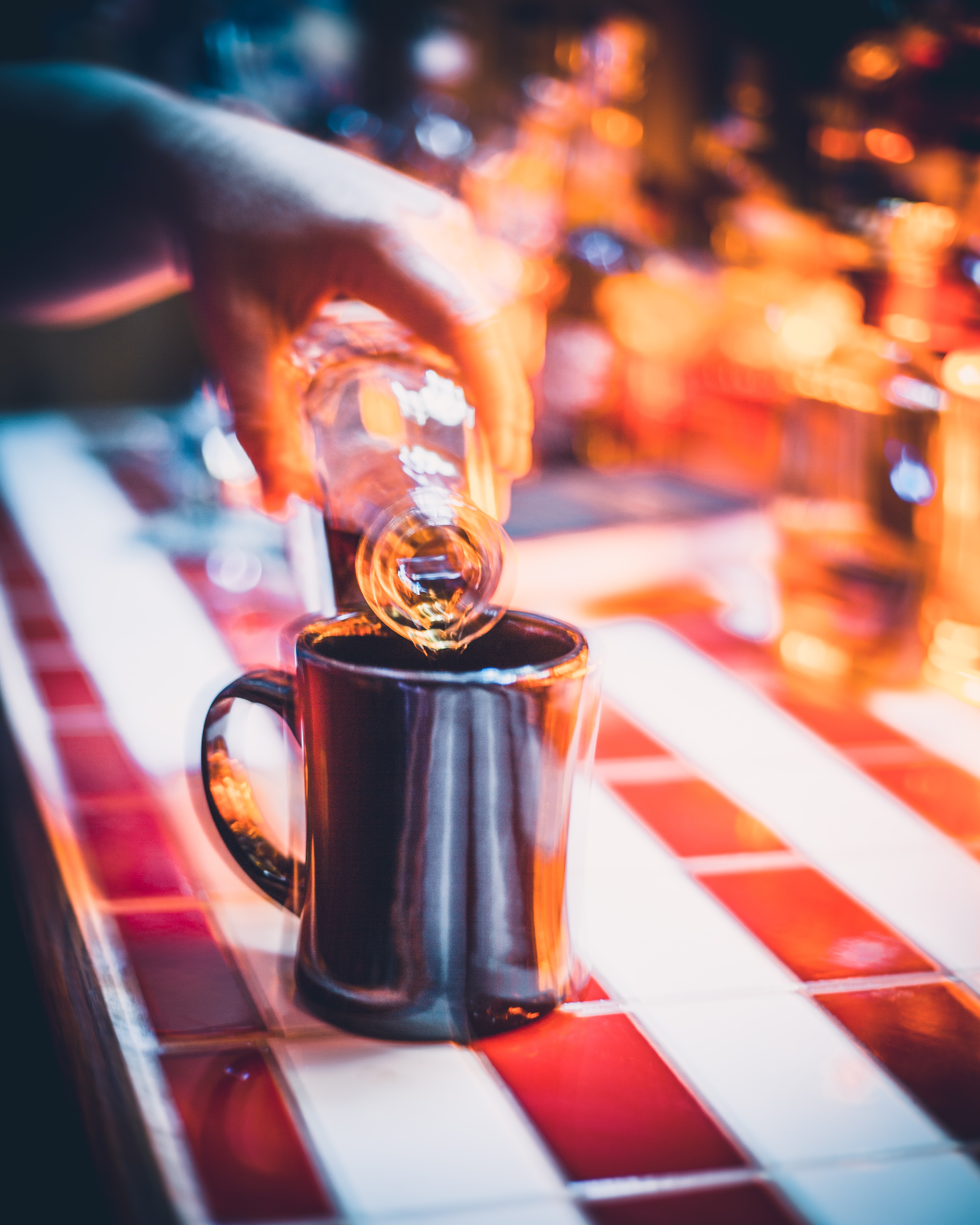 Blurry image of someone pouring alcohol into a mug on bar; image by Nick Rickert, via Unsplash.com.