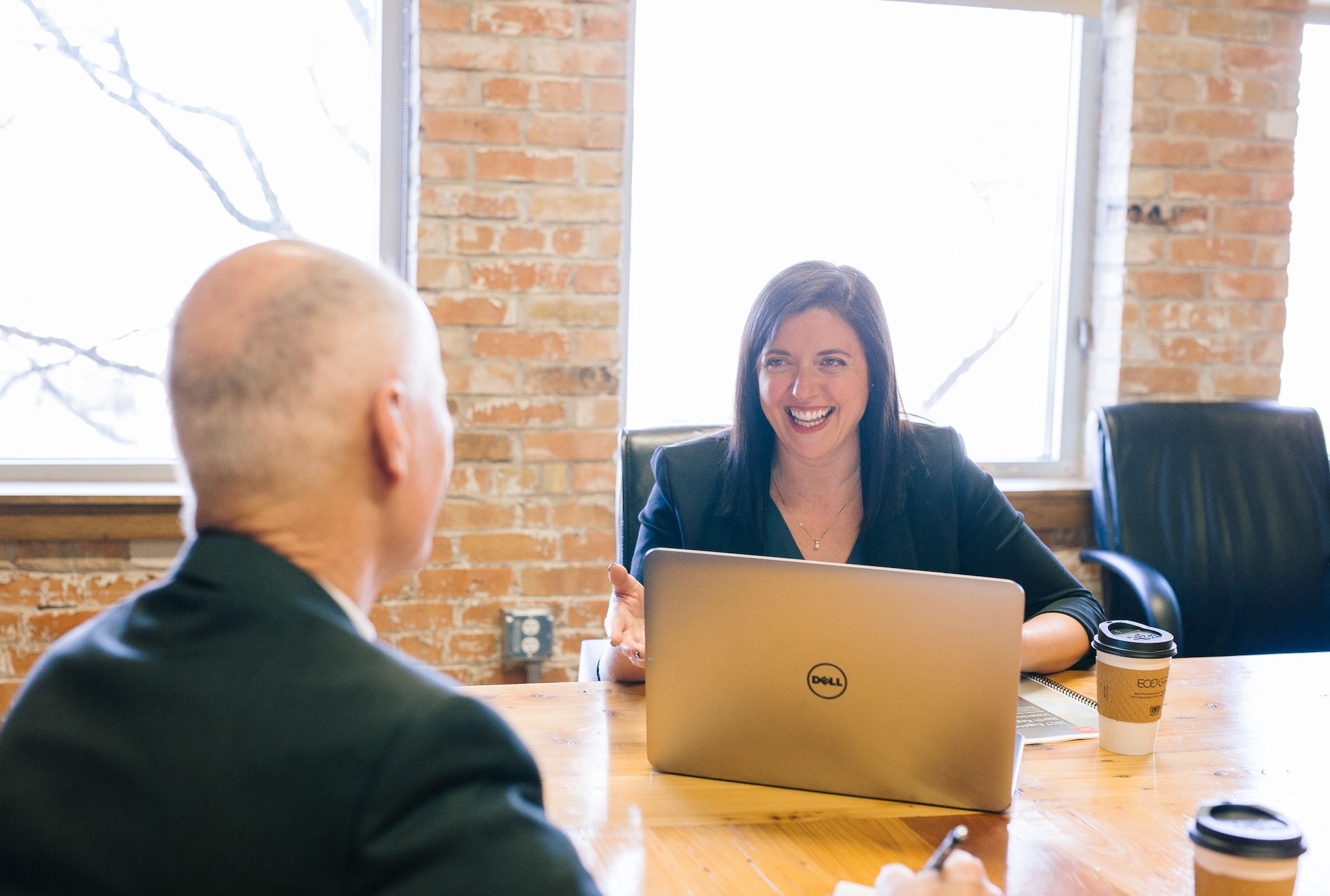 Man facing woman with laptop; image by Amy Hirschi, via Unsplash.com.