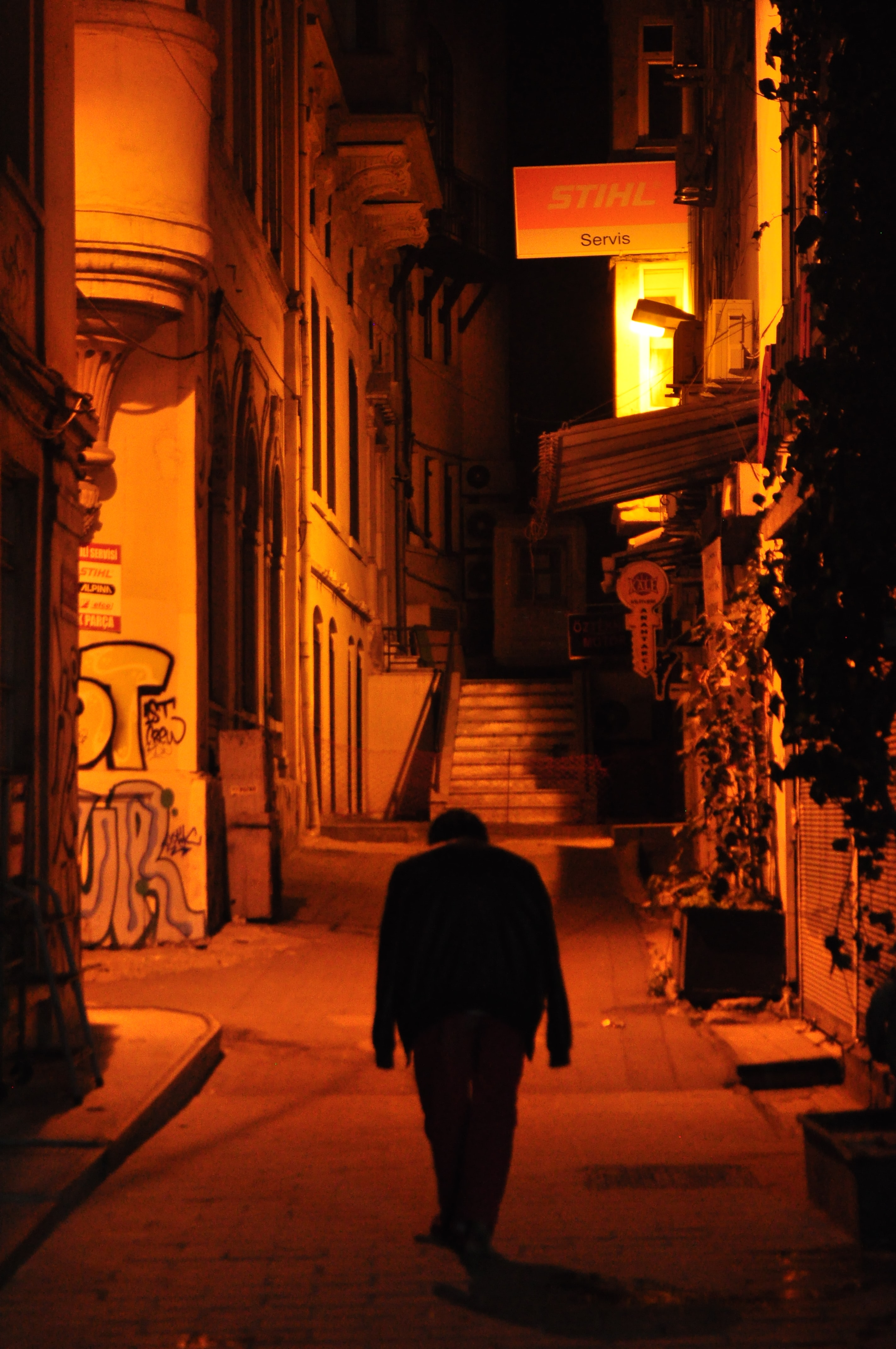 Man walking down deserted street at night; image by Aliagha Shirinov, via Unsplash.com.