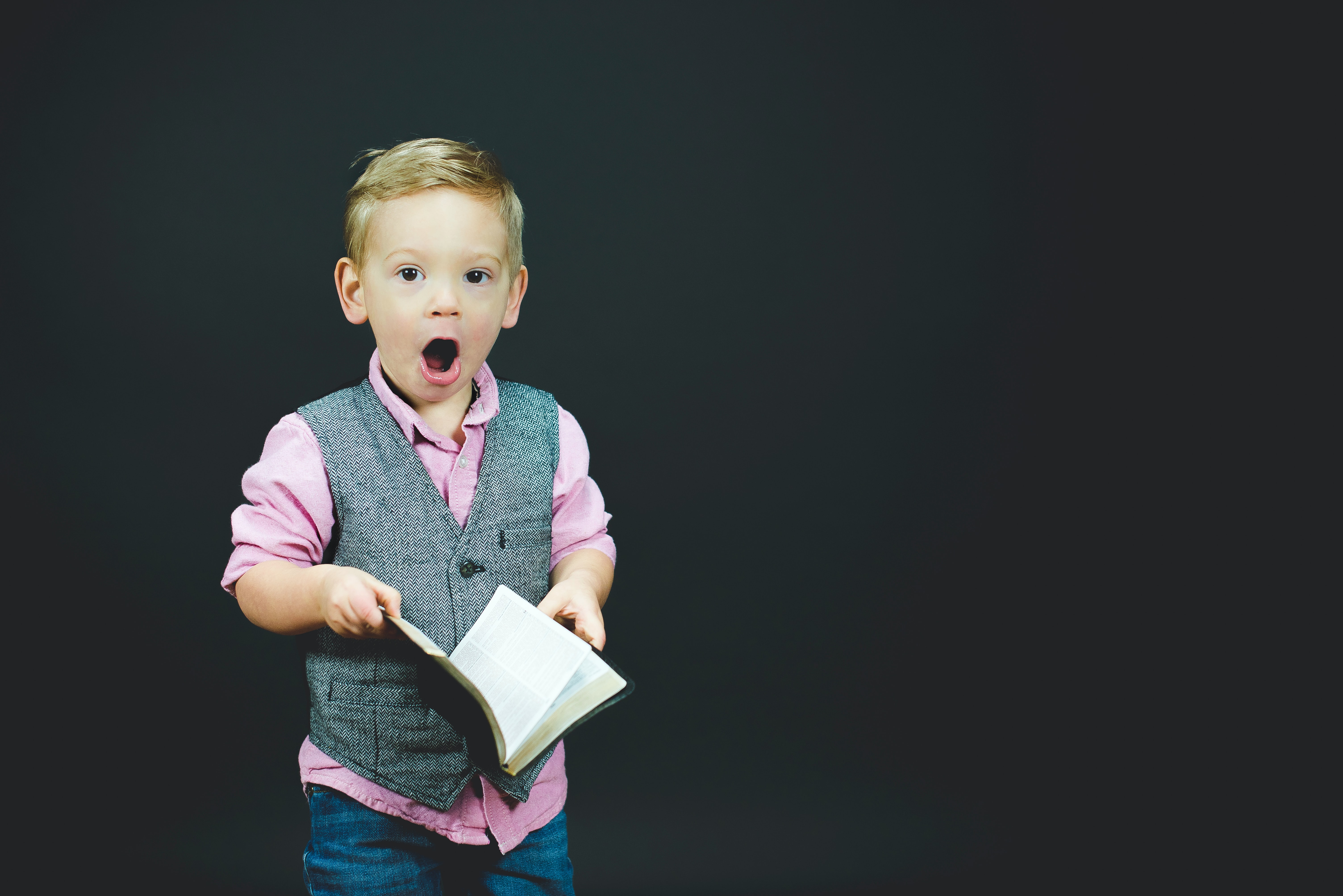 Little boy with book looking surprised; image by Ben White, via Unsplash.com.