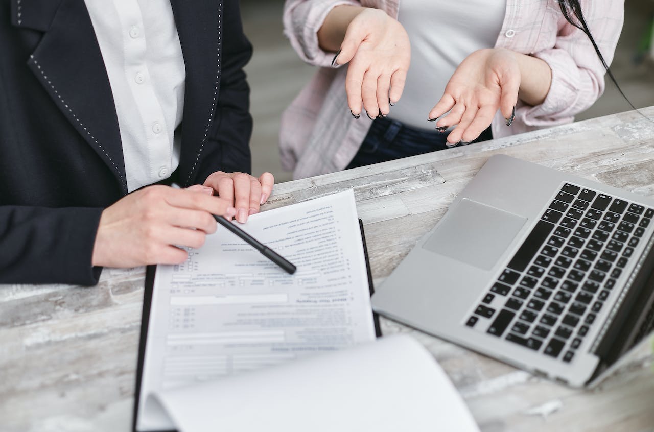 Two women reviewing paperwork; image by Mikhail Nilov, via Pexels.com.