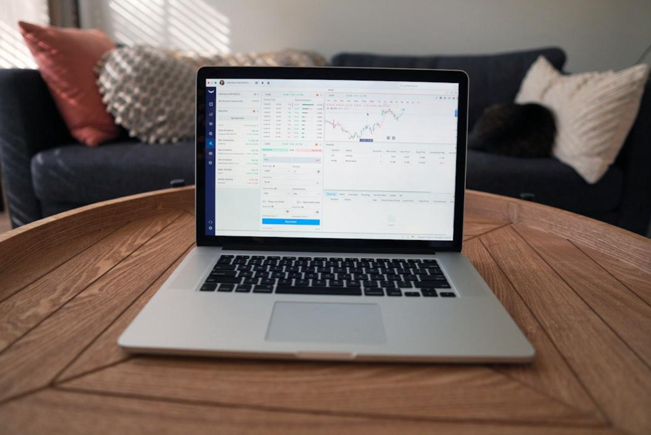 Laptop on table, stock information on screen; image by Joshua Mayo, via Unsplash.com.